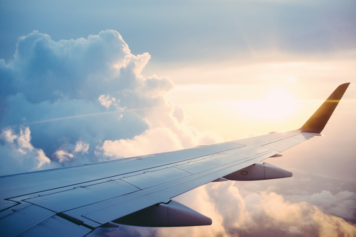 Airplane wing above the clouds at sunset — fully funded scholarships and study abroad for Pakistani students